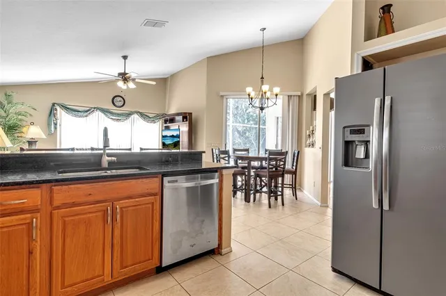 a kitchen with stainless steel appliances kitchen island granite countertop a table chairs and a refrigerator