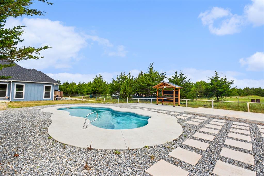530 P R 491 Leonard, TX 75452 - Photo 29 of 35 Freeform swimming pool with concrete decking, surrounded by gravel landscaping