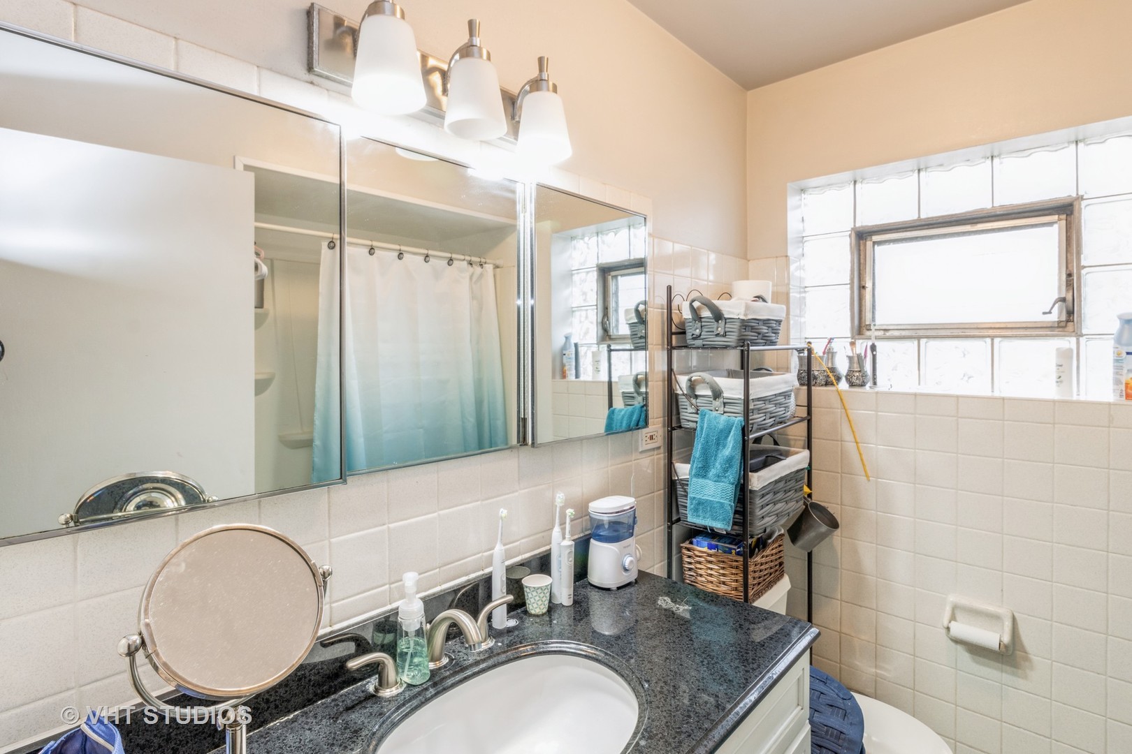 8517 West Foster Avenue Chicago, IL 60656 - Photo 6 of 21 a bathroom with a granite countertop sink a mirror and a shower