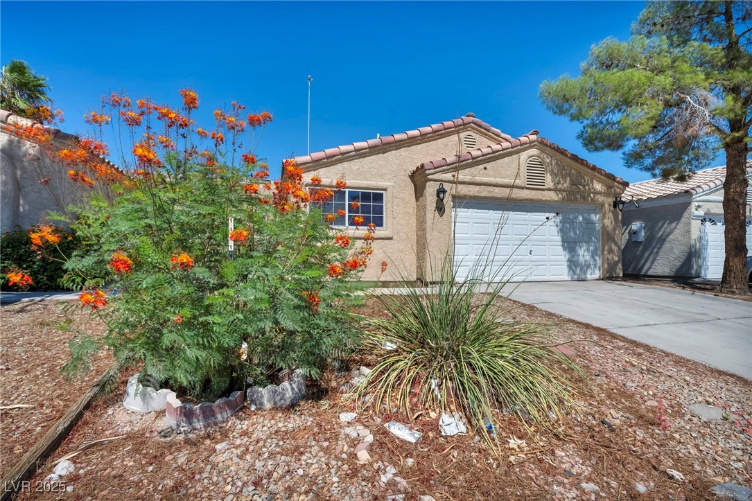 View of front of property with stucco siding, a garage, driveway, and a tiled roof