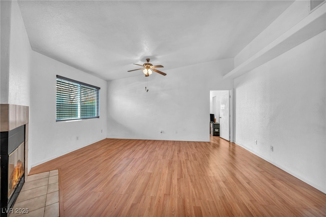 2165 St Paul Way Las Vegas, NV 89104 - Photo 12 of 45 Unfurnished living room featuring a tile fireplace, light wood finished floors, and a ceiling fan