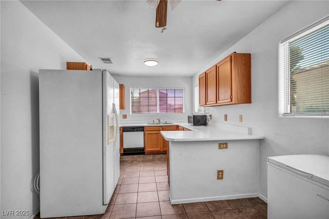 2165 St Paul Way Las Vegas, NV 89104 - Photo 14 of 45 Kitchen with white appliances, light countertops, tile patterned floors, and a peninsula