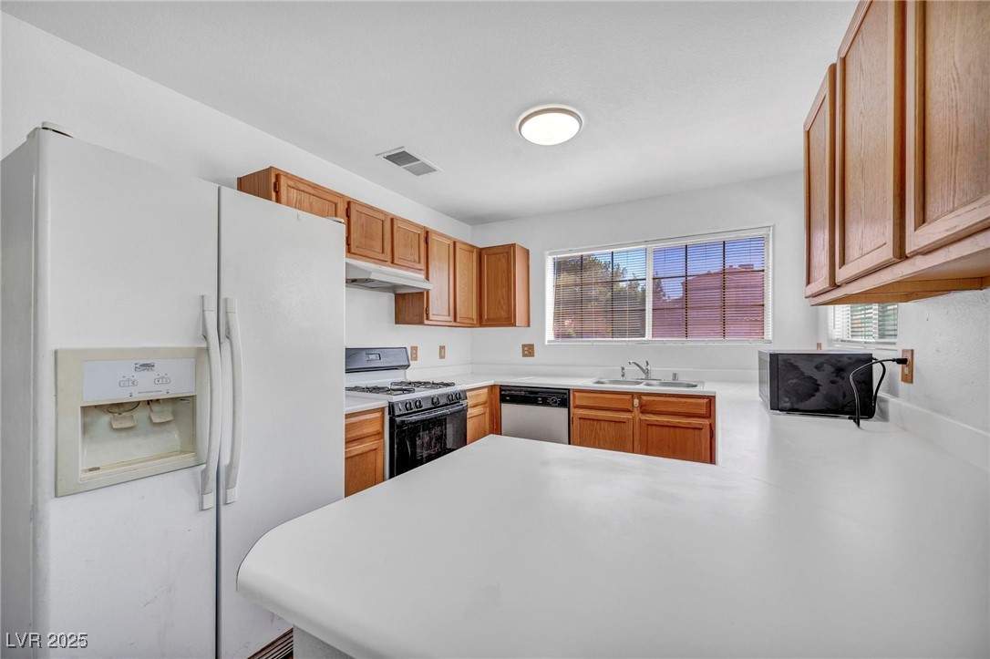 2165 St Paul Way Las Vegas, NV 89104 - Photo 15 of 45 Kitchen featuring white appliances, under cabinet range hood, healthy amount of natural light, and a peninsula