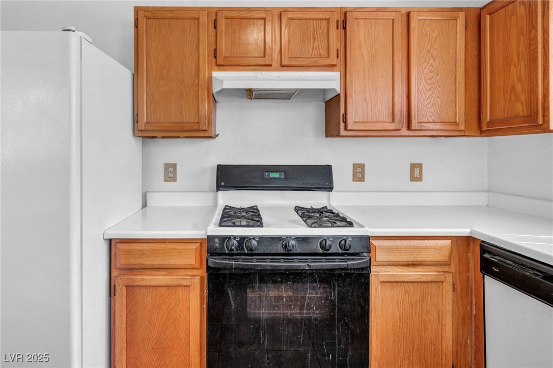 2165 St Paul Way Las Vegas, NV 89104 - Photo 17 of 45 Kitchen with white appliances, under cabinet range hood, light countertops, and brown cabinets