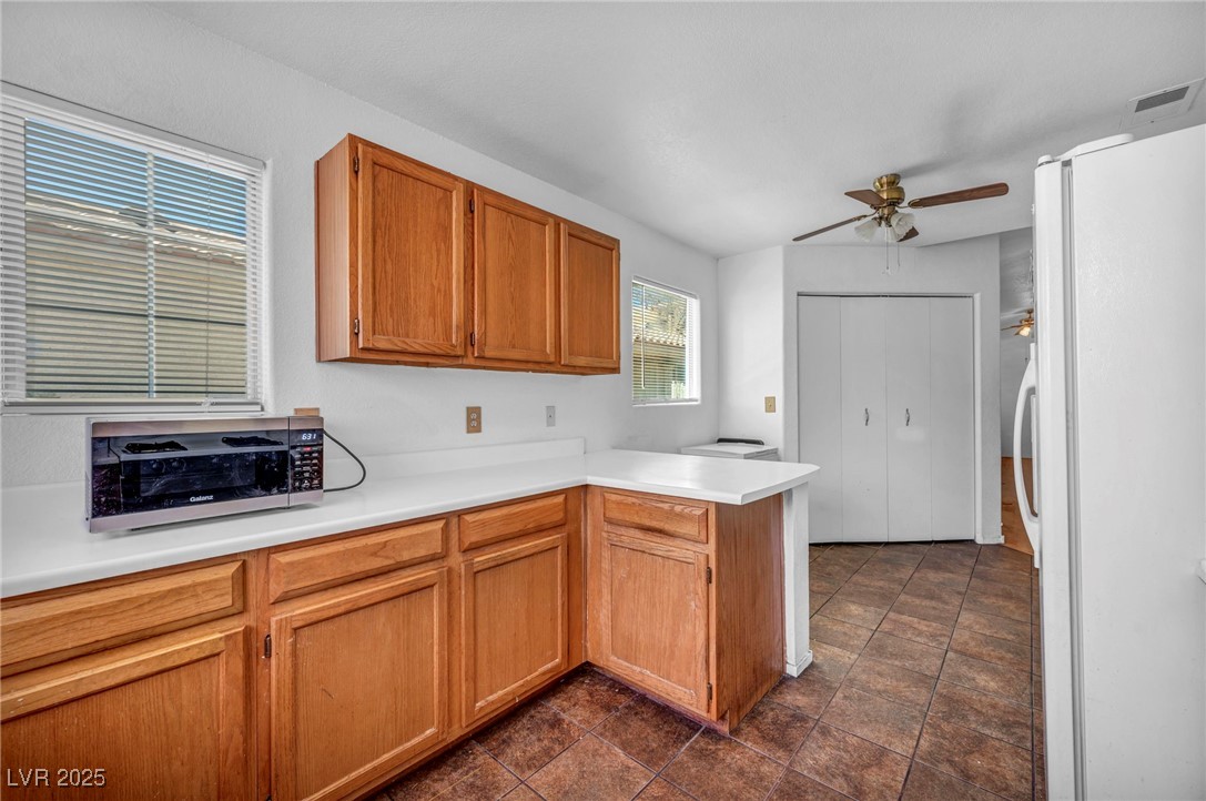 2165 St Paul Way Las Vegas, NV 89104 - Photo 18 of 45 Kitchen featuring freestanding refrigerator, a peninsula, ceiling fan, and light countertops