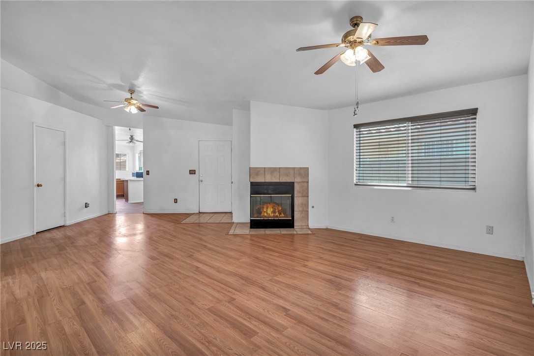 2165 St Paul Way Las Vegas, NV 89104 - Photo 7 of 45 Unfurnished living room featuring a ceiling fan, light wood-style floors, and a tile fireplace
