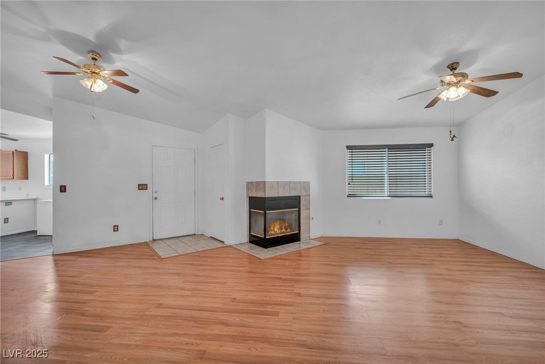 2165 St Paul Way Las Vegas, NV 89104 - Photo 8 of 45 Unfurnished living room with ceiling fan, light wood finished floors, a fireplace, and lofted ceiling