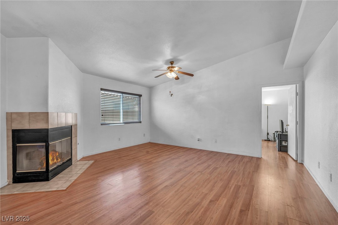 2165 St Paul Way Las Vegas, NV 89104 - Photo 9 of 45 Unfurnished living room featuring light wood-type flooring, a fireplace, and ceiling fan