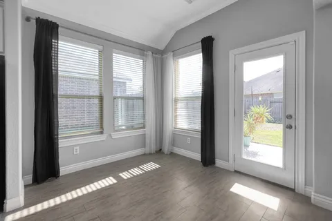 a view of an empty room with a window and wooden floor