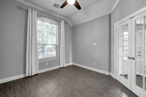 an empty room with wooden floor chandelier fan and windows