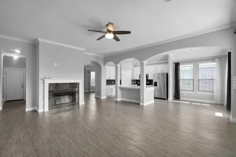 a view of a livingroom with a fireplace a ceiling fan and windows