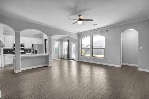 a view of an empty room with wooden floor and a kitchen