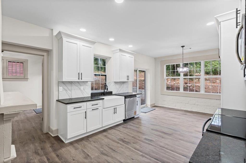 203 Church Street Northeast Rome, GA 30161 - Photo 11 of 36 a large kitchen with stainless steel appliances granite countertop a stove a sink and white cabinets with wooden floor next to windows