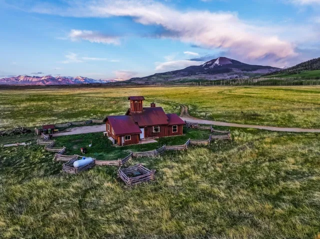 a backyard of a house with lots of green space and two chairs