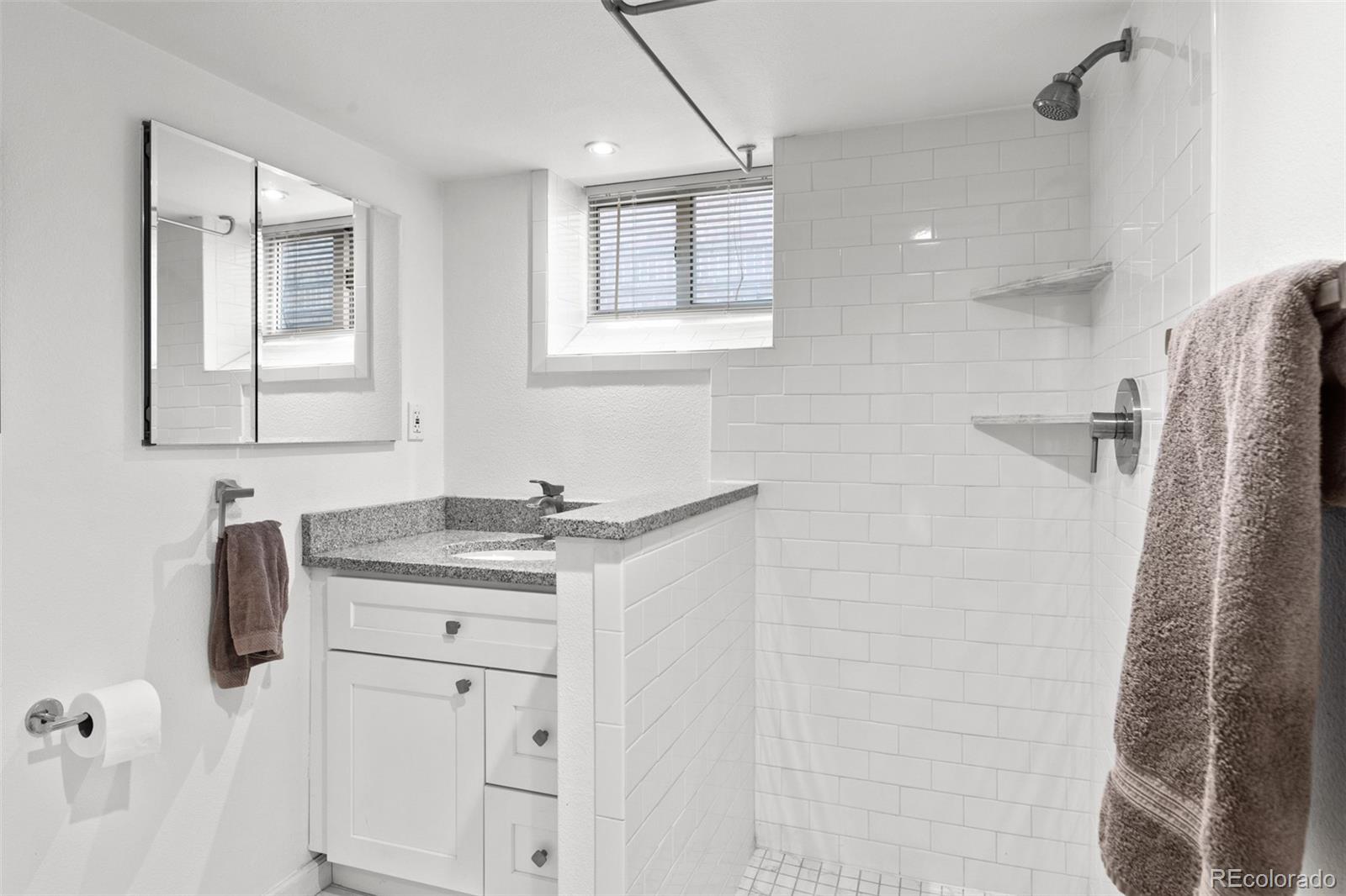 3517 York Street Denver, CO 80205 - Photo 36 of 45 a bathroom with a granite countertop sink a mirror and shower
