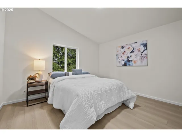 a spacious bedroom with a bed and a painting on the wall