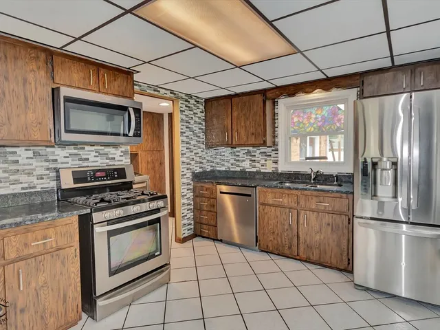 a kitchen with granite countertop stainless steel appliances a stove sink and microwave