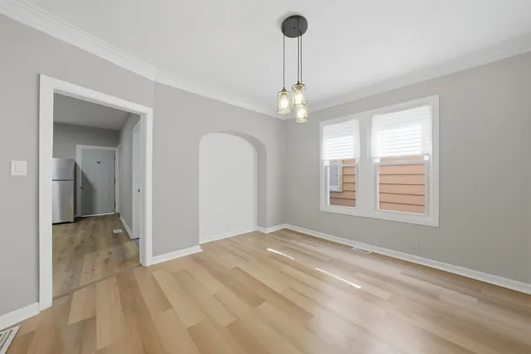 a view of an empty room with window and chandelier fan