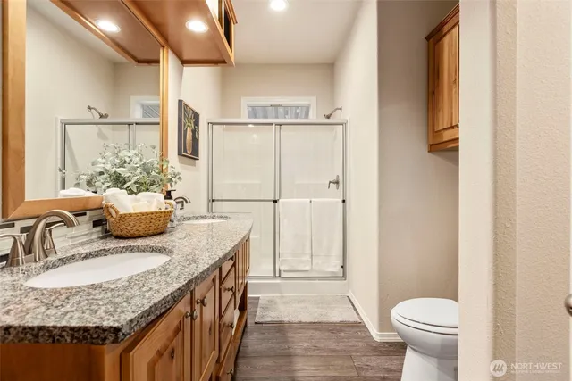 a bathroom with a granite countertop sink a toilet a mirror and shower