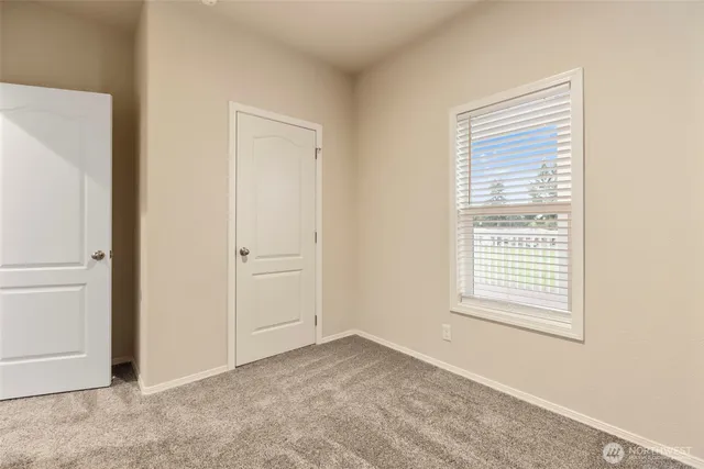 a view of an empty room with closet and a window