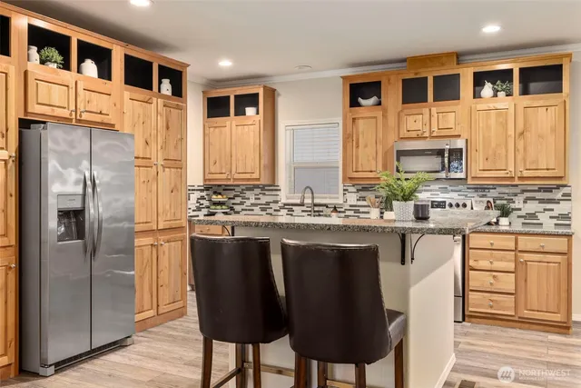 a kitchen with stainless steel appliances granite countertop a refrigerator a stove and a sink with wooden cabinets