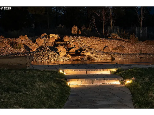 a kitchen with stainless steel appliances kitchen island granite countertop a refrigerator a stove a sink and a dining table with wooden floor