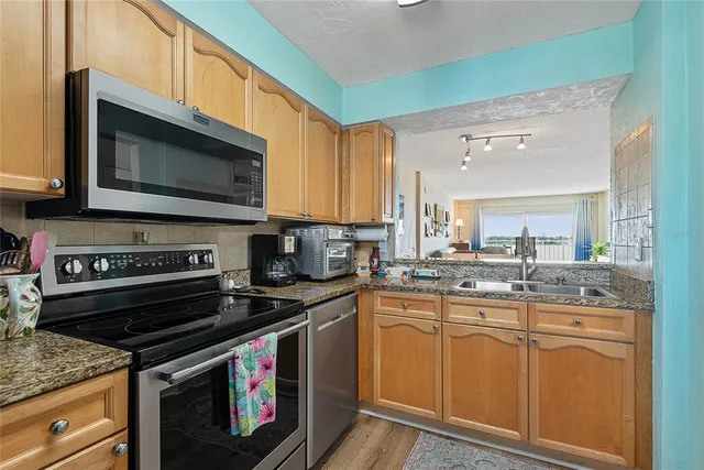 a kitchen with stainless steel appliances granite countertop a stove microwave and sink