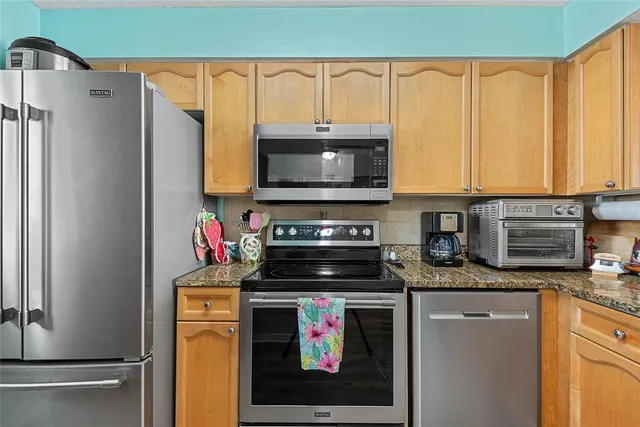 a kitchen with stainless steel appliances granite countertop a stove a refrigerator and a microwave