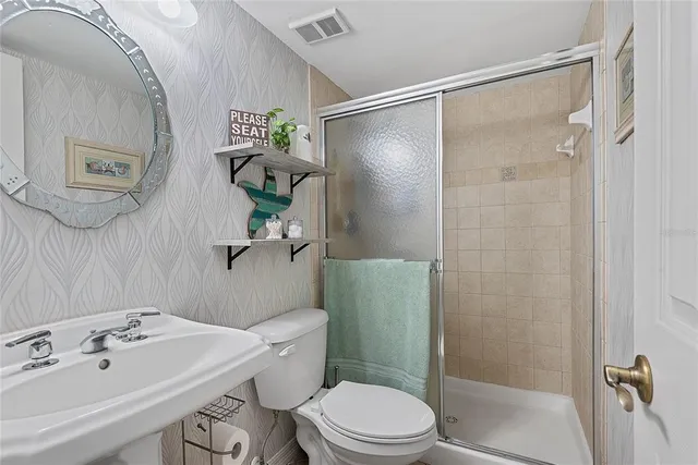 a bathroom with a shower a sink a toilet and a mirror