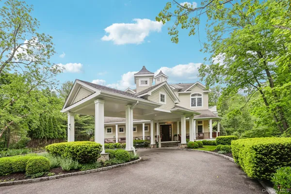 a view of a white house with a big yard and large trees