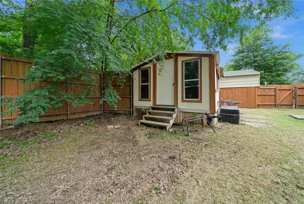 a backyard of a house with barbeque oven and trees