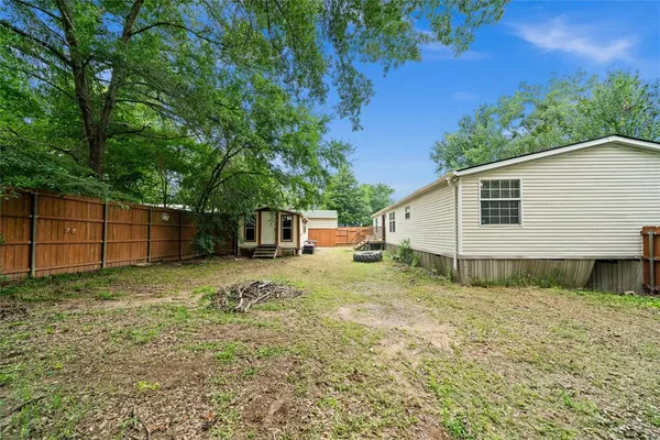 a view of a backyard with large trees and a barn