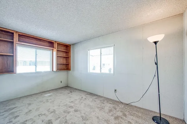 an empty room with windows and ceiling fan
