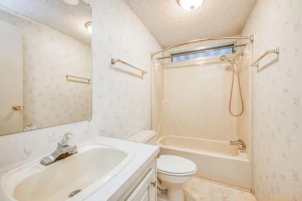 an empty room with chandelier fan and windows