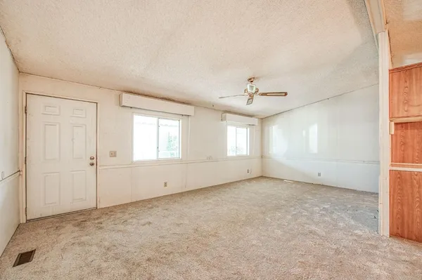 an empty room with windows and ceiling fan
