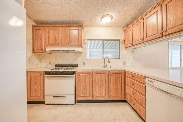 a kitchen with granite countertop white cabinets and white appliances