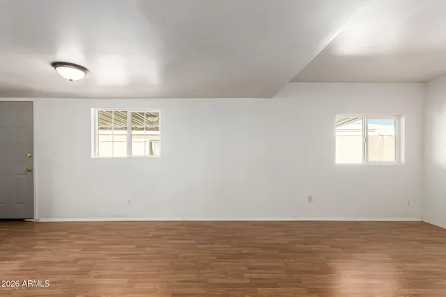 an empty room with wooden floor and windows