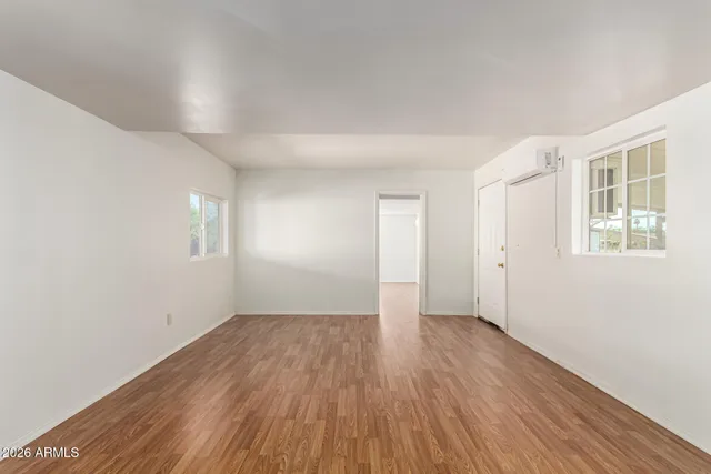 an empty room with wooden floor and windows