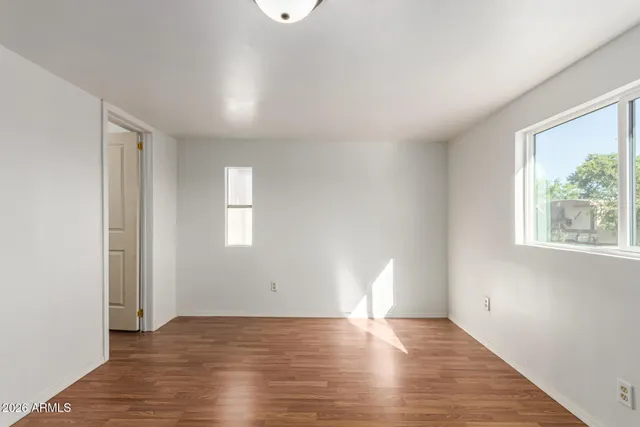 an empty room with wooden floor and windows