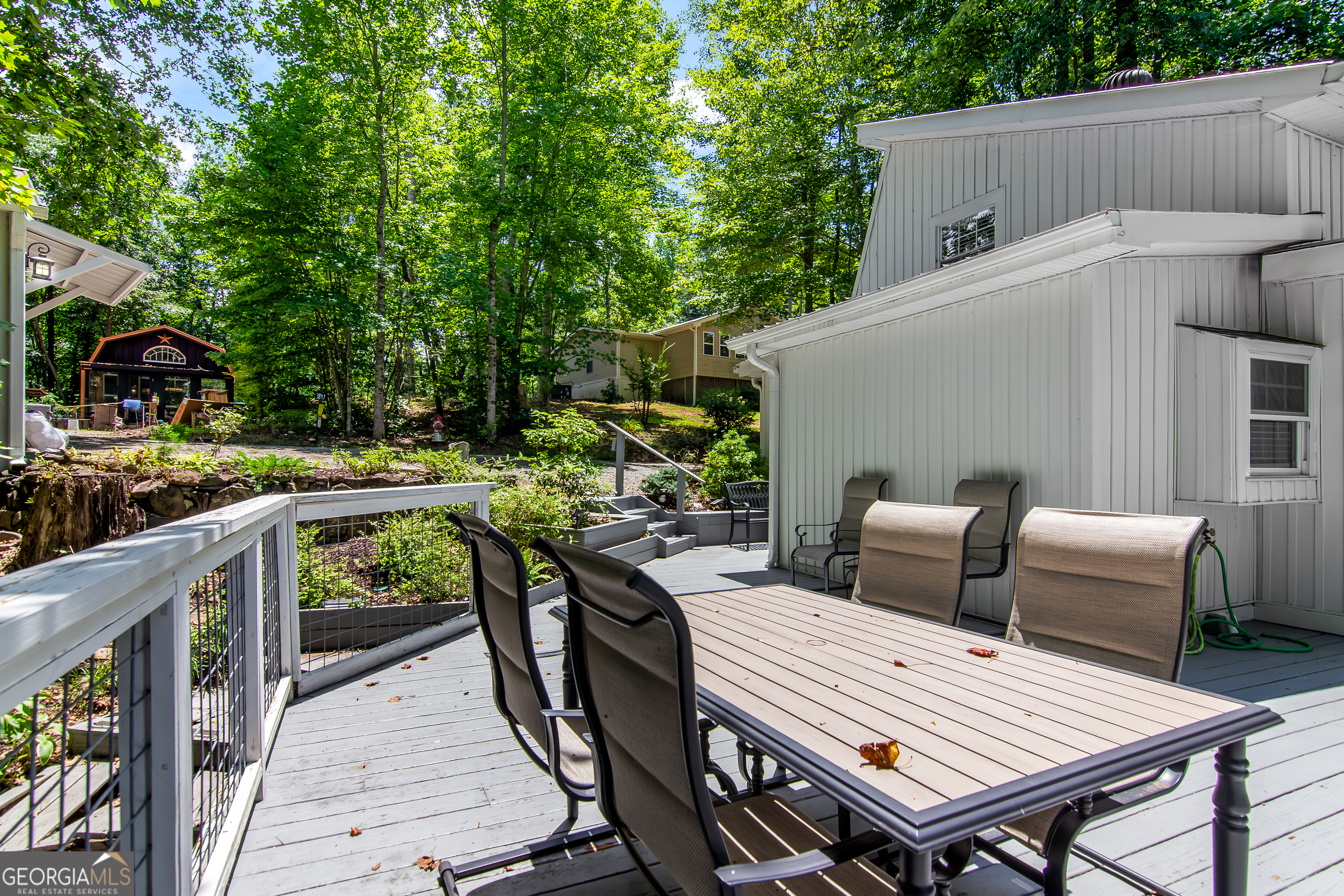 1056 Sky Hawk Mountain Road Hiawassee, GA 30546 - Photo 34 of 50 a view of a patio with table and chairs with wooden floor and fence