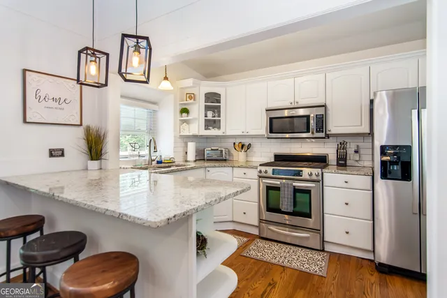 a kitchen with stainless steel appliances granite countertop a sink stove microwave and refrigerator