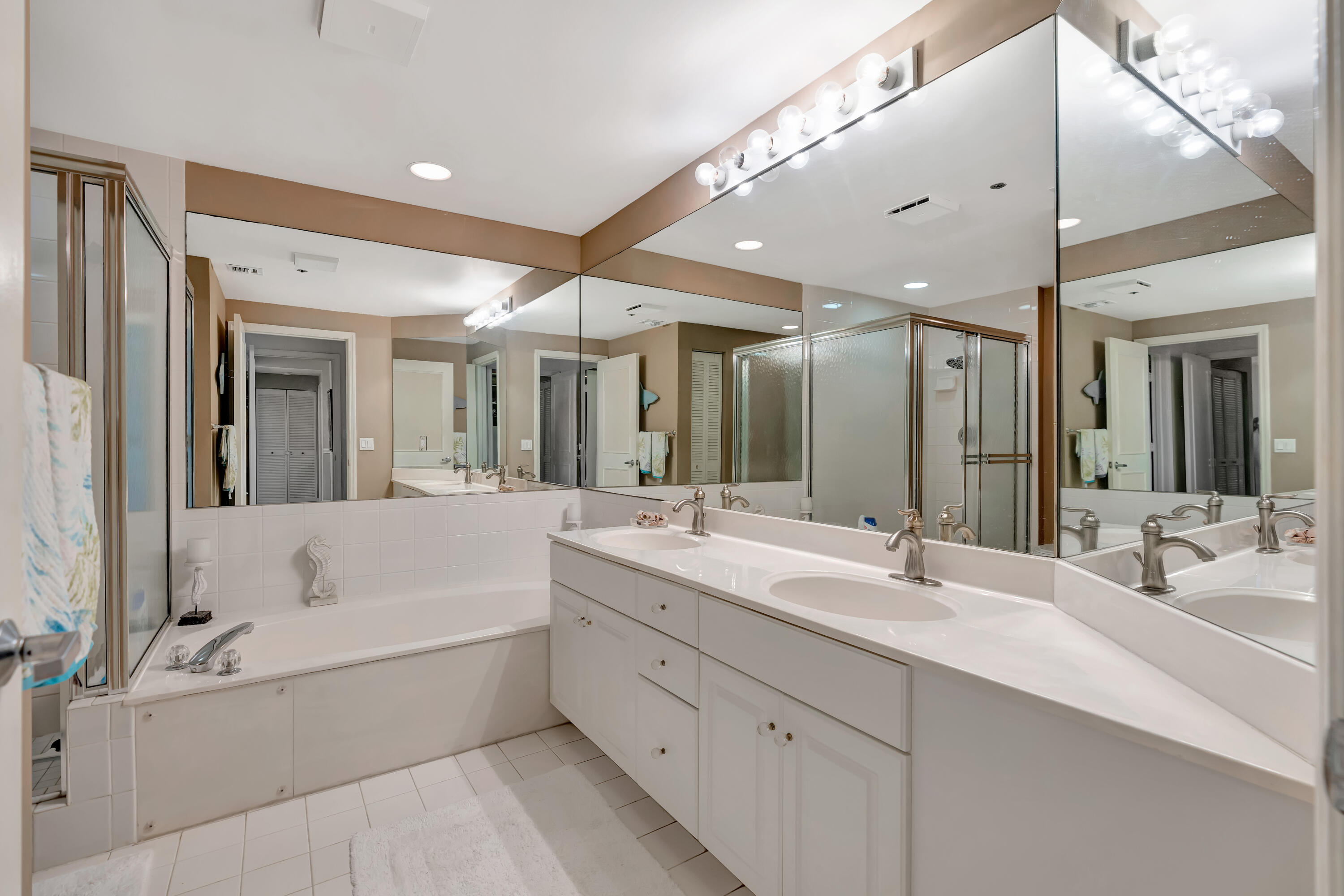 2000 Florida A1A, Unit N302 Jupiter, FL 33477 - Photo 37 of 65 a bathroom with a tub a double vanity sink and mirror