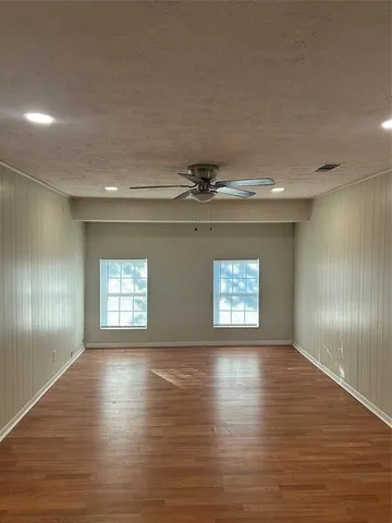 a view of an empty room with window and wooden floor