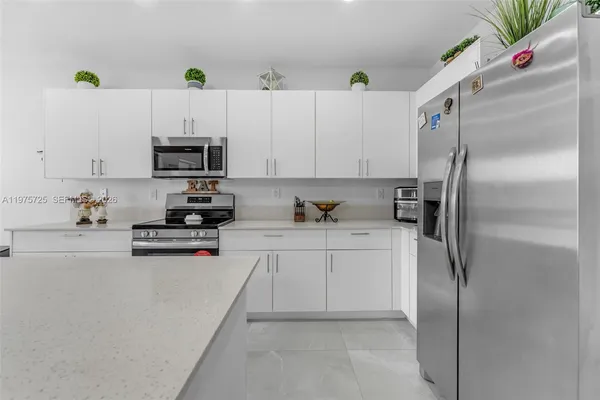 a kitchen with stainless steel appliances a refrigerator sink and white cabinets