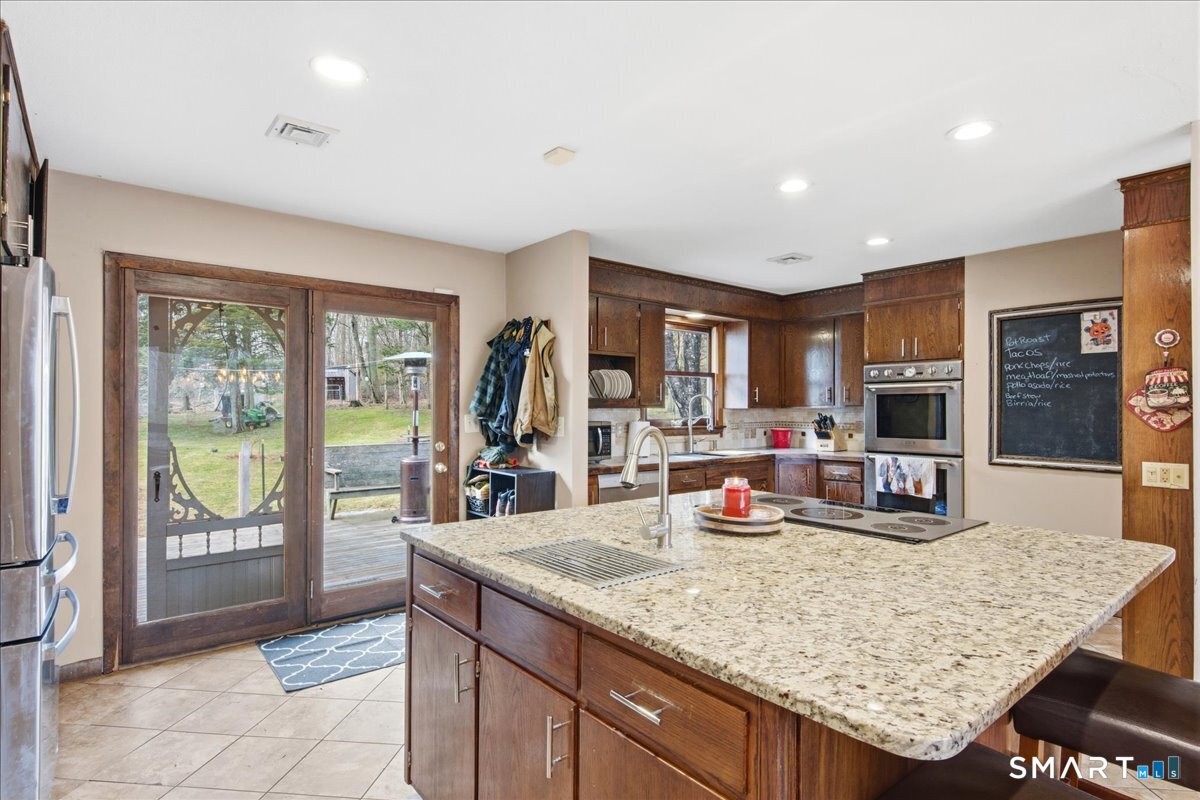 110 Butlertown Road Waterford, CT 06385 - Photo 6 of 35 a kitchen with granite countertop a refrigerator a stove a sink a dining table and chairs with wooden floor