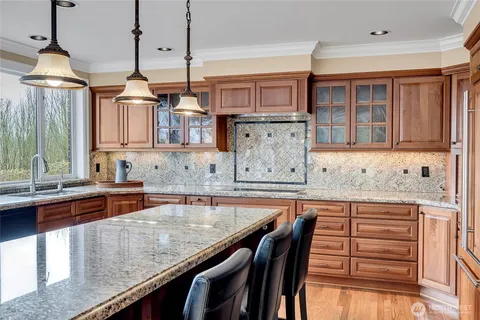 a kitchen with granite countertop a stove a sink and a wooden cabinets