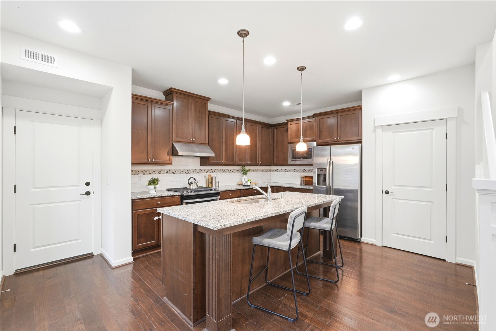 4413 185th Place Southeast Bothell, WA 98012 - Photo 11 of 40 a kitchen with stainless steel appliances a stove a refrigerator a sink dishwasher and a dining table with wooden floor