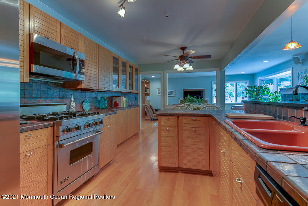 2 Flora Drive Holmdel, NJ 07733 - Photo 16 of 34 a kitchen with stainless steel appliances granite countertop a sink a stove top oven a chimney cabinets and wooden floor