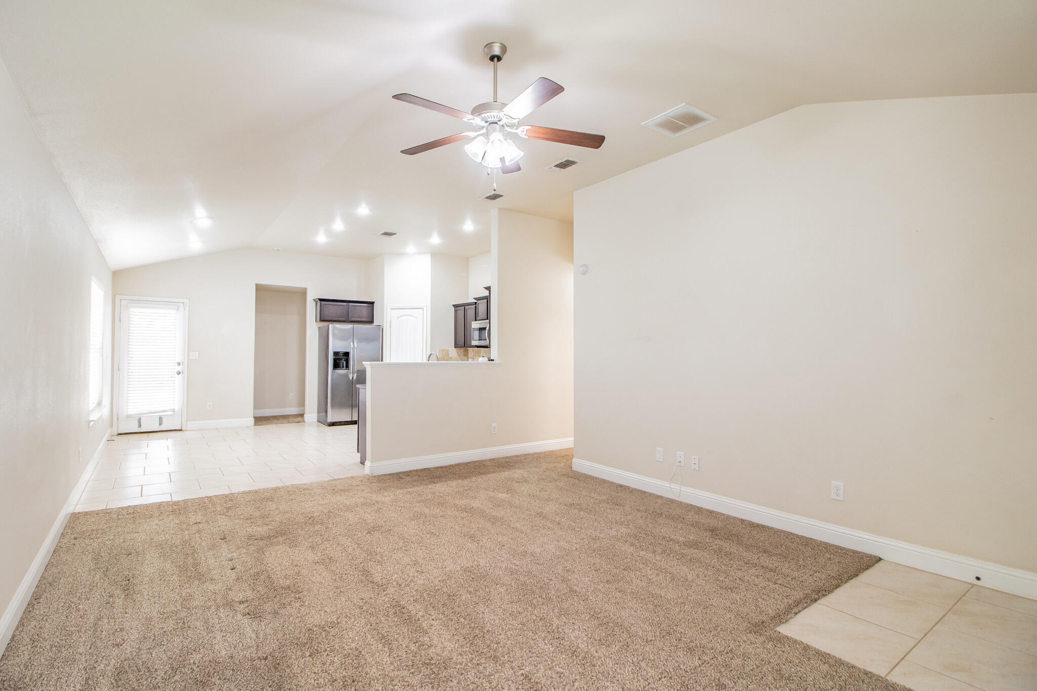 7409 101st Street Lubbock, TX 79424 - Photo 5 of 22 an empty room with fan and way to kitchen
