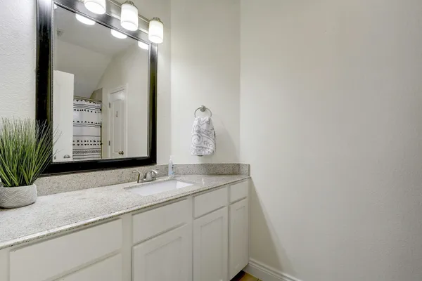 a bathroom with a granite countertop sink and a mirror